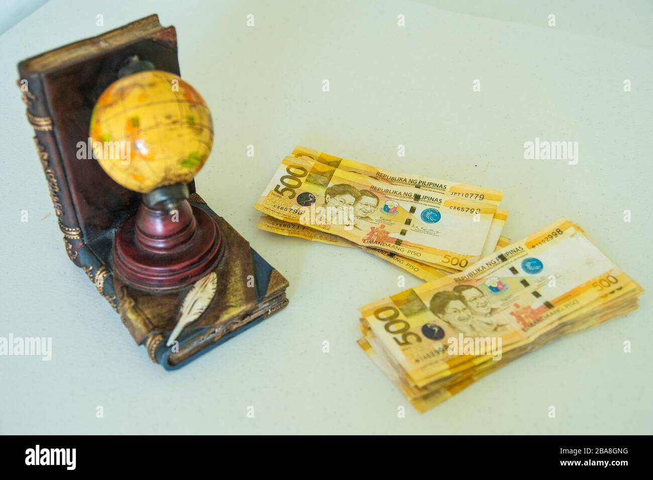 Philippine money on table with a globe beside it Stock Photo