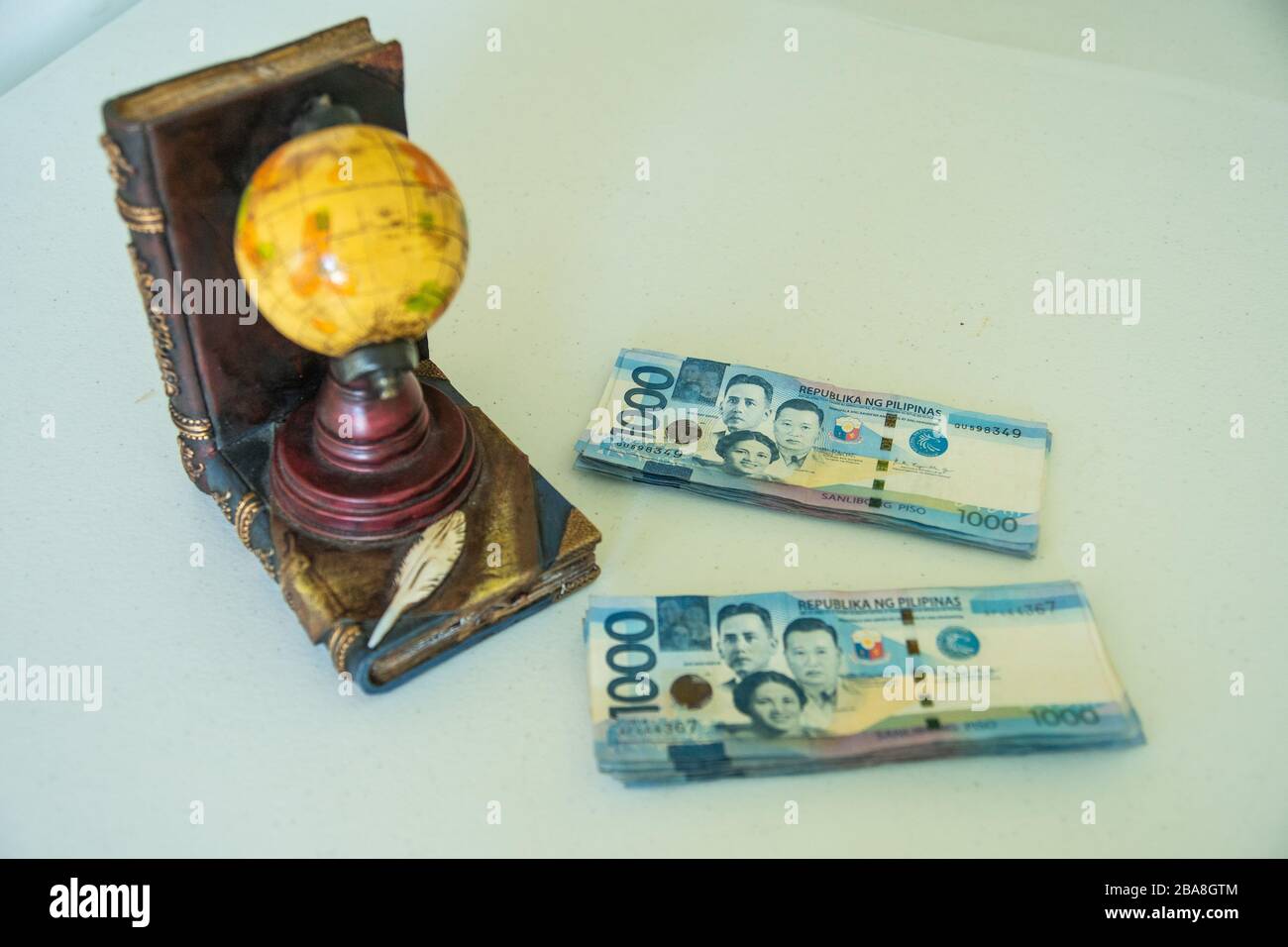 Philippine money on table with a globe beside it Stock Photo