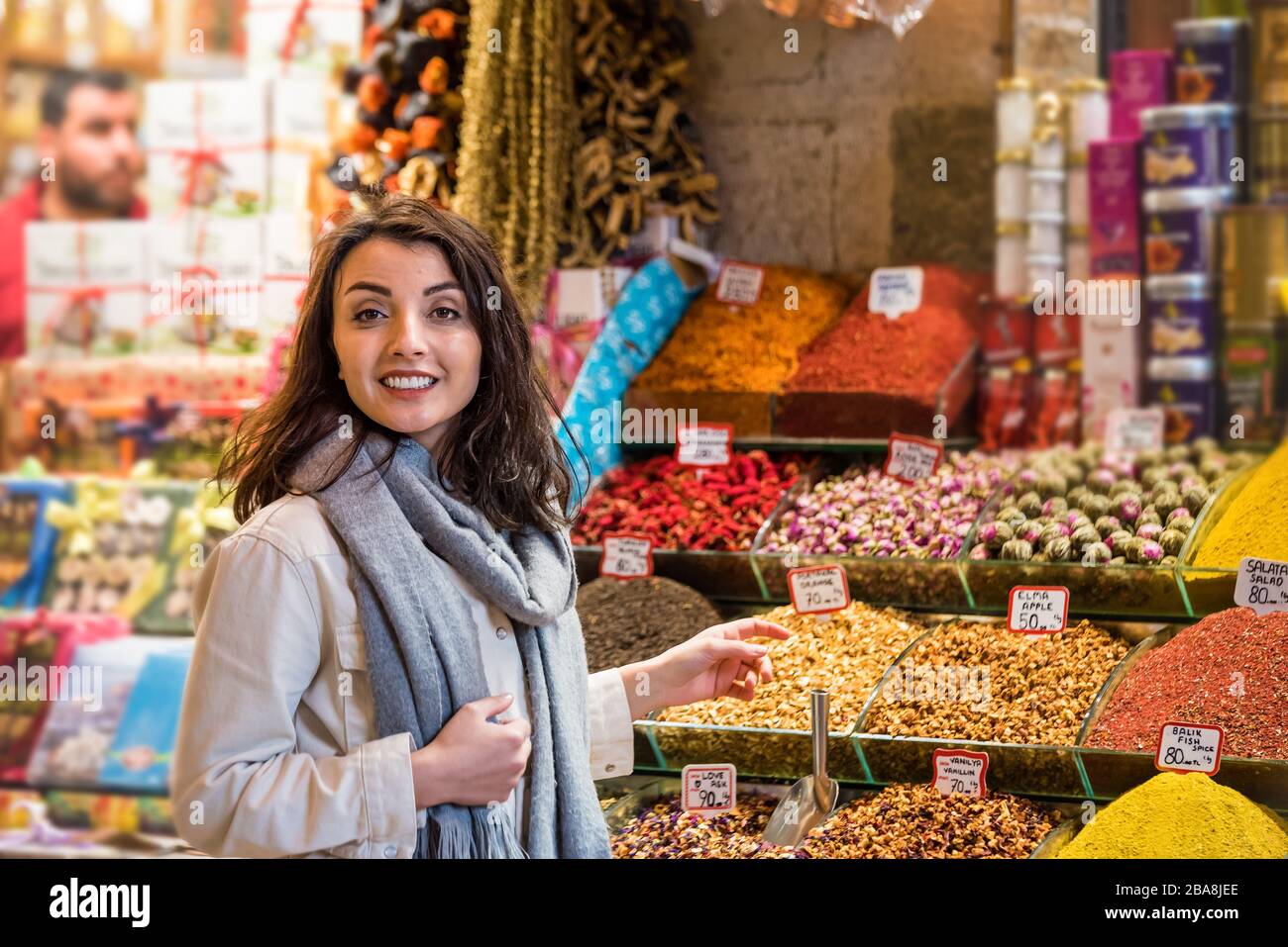 Beautiful woman shows dried herbs or flowers while standing in front of a spice stall sold on stall in Egypt Bazaar in Eminonu,Istanbul,Turkey Stock Photo