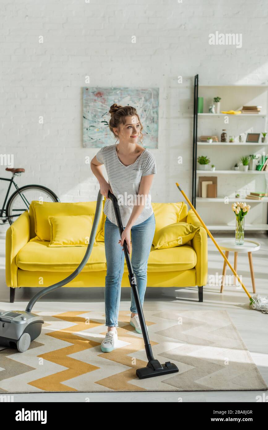 happy young woman cleaning carpet with vacuum cleaner Stock Photo - Alamy