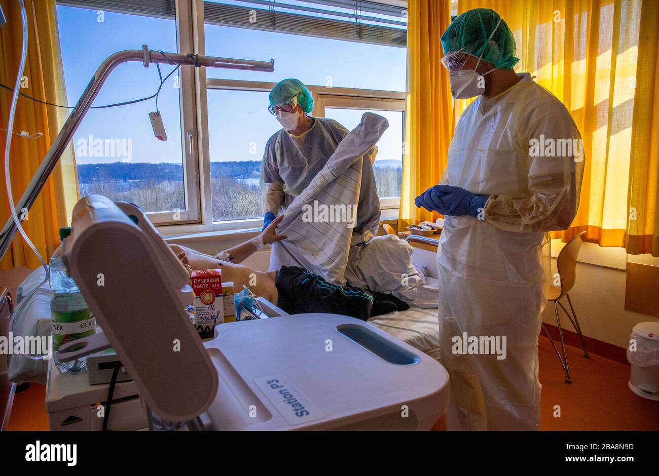 Schwerin, Germany. 26th Mar, 2020. Senior physician Muhammad Babbili talks to a patient in the isolation ward for coronavirus treatments at the hospital. In the isolation wards, the doctors, nurses and staff wear protective suits, glasses and mouthguards. The Helios Clinic is preparing for an increase in corona cases. Credit: Jens Büttner/dpa-Zentralbild/dpa/Alamy Live News Stock Photo