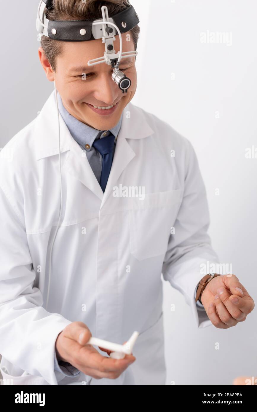 smiling otolaryngologist with ent headlight holding nasal speculum Stock Photo