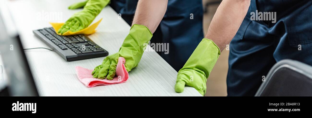 partial view of cleaners in rubber gloves cleaning office desk and computer keyboard Stock Photo