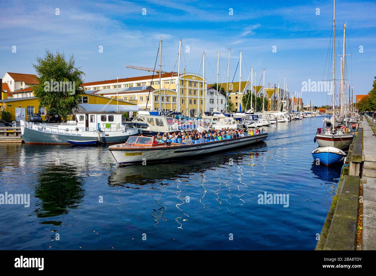 Christianshavn Canal in Copenhagen Denmark with vessels along both quays and harbour cruise vessel passing through Stock Photo
