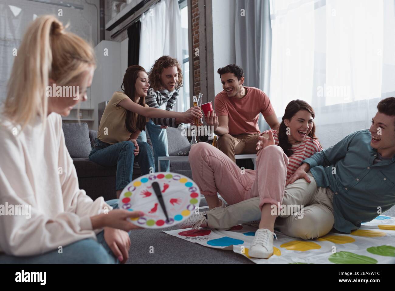 KYIV, UKRAINE - JANUARY 27, 2020: selective focus of girl holding moves board while cheerful friends playing twister game Stock Photo