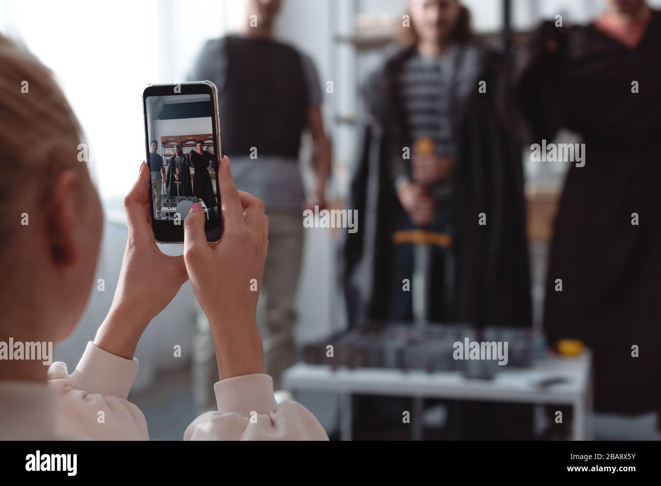 selective focus of girl taking photo of men in fairy costumes on smartphones Stock Photo