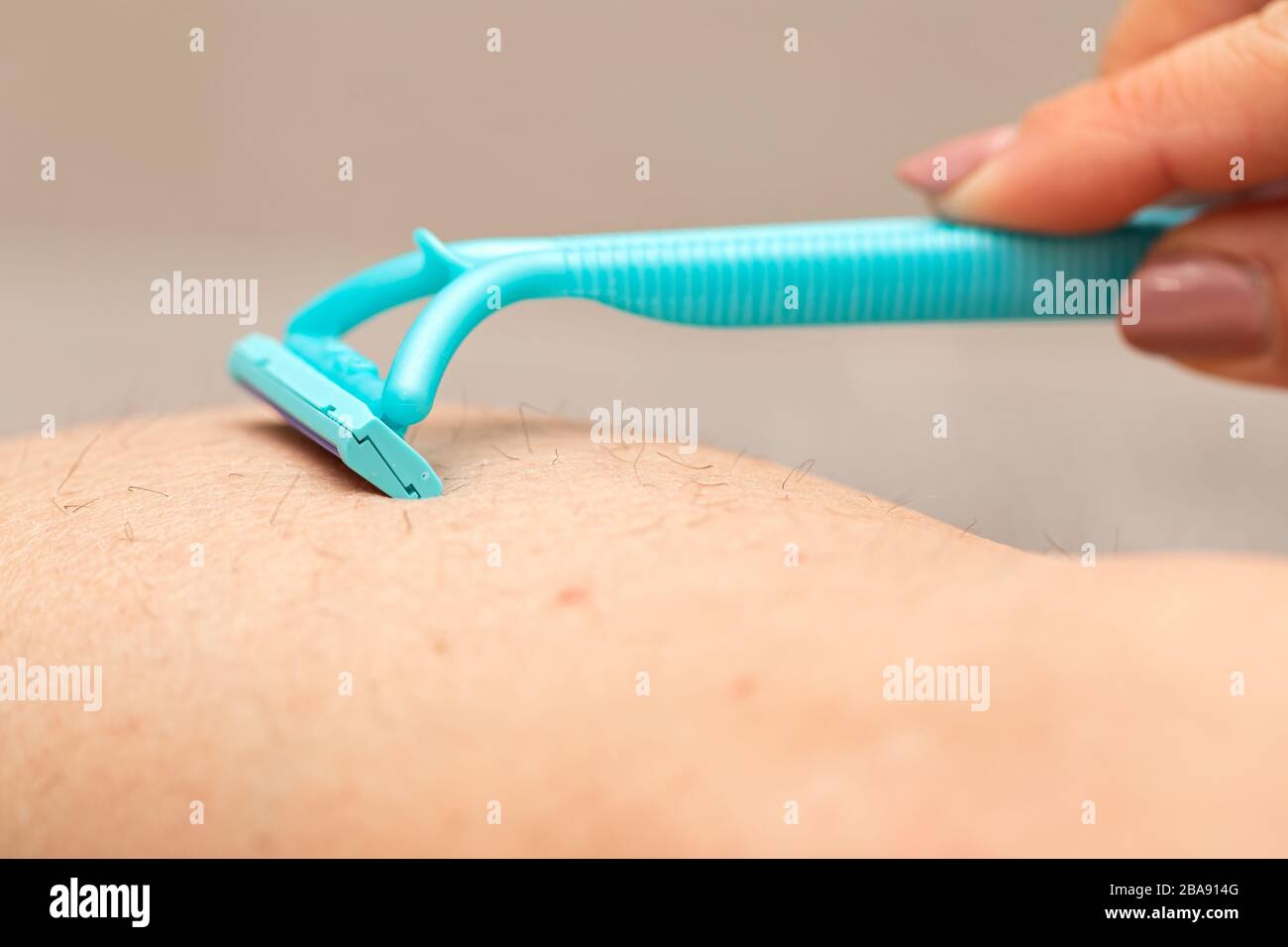 Close up picture of woman holding razor, shaving her hairy leg with ...