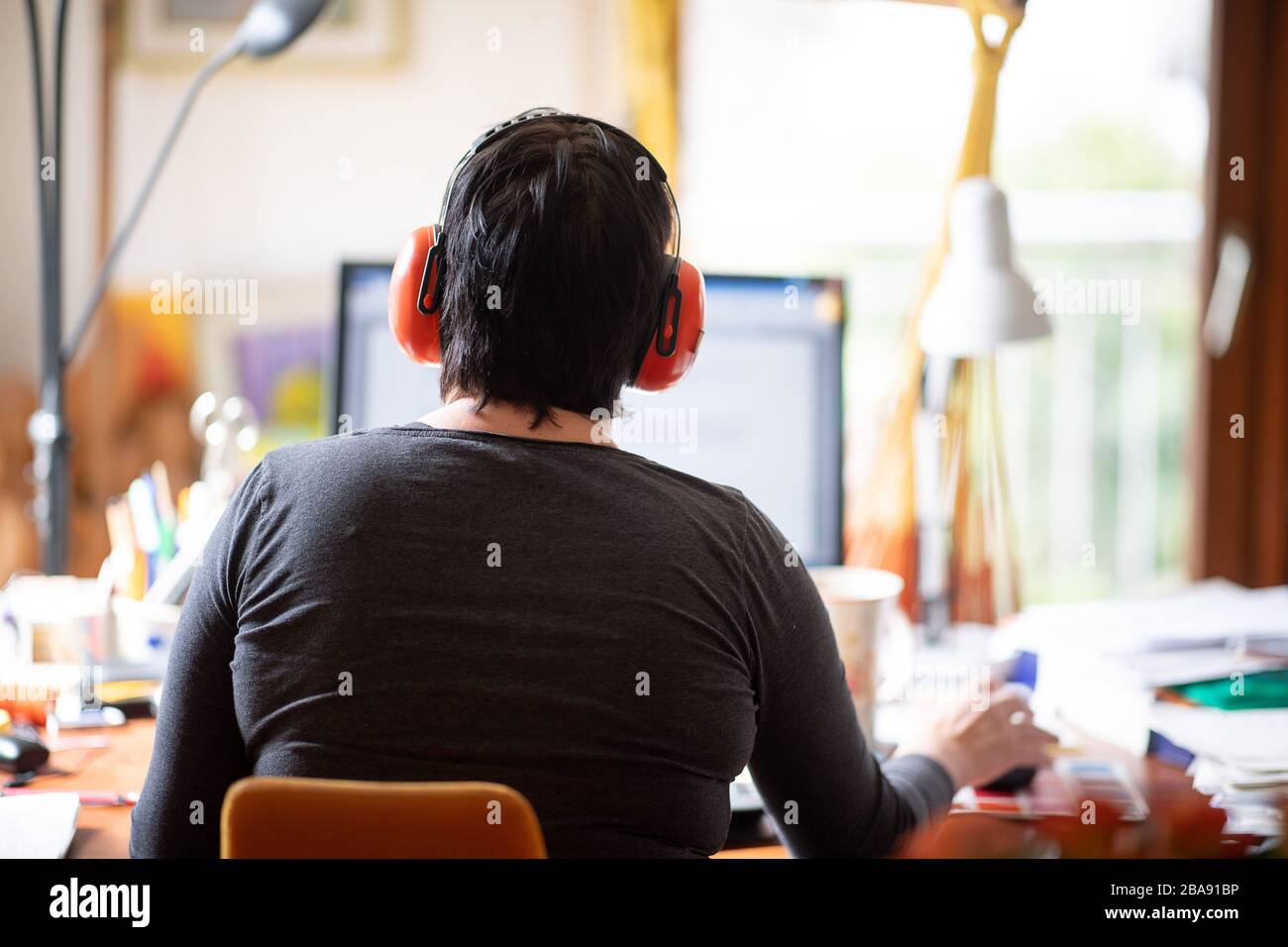 Waldenbuch, Germany. 26th Mar, 2020. A woman works with hearing protection in her home office. To slow the spread of the coronavirus, many workers work from home. Credit: Sebastian Gollnow/dpa/Alamy Live News Stock Photo