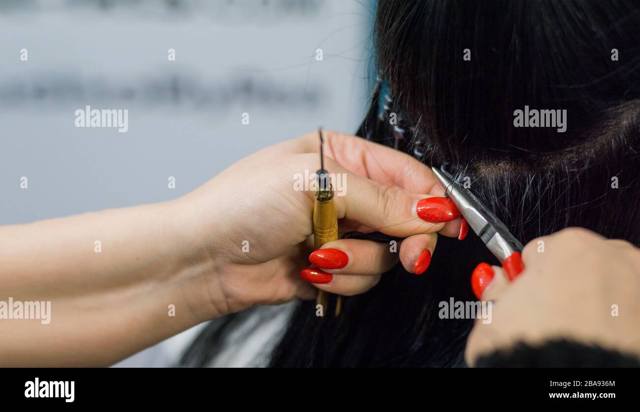 Professional woman applying hair extensions with different types of grips. Nano rings extensions