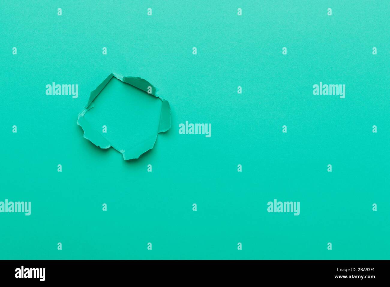Green color background with hole in the paper. Copy space Stock Photo