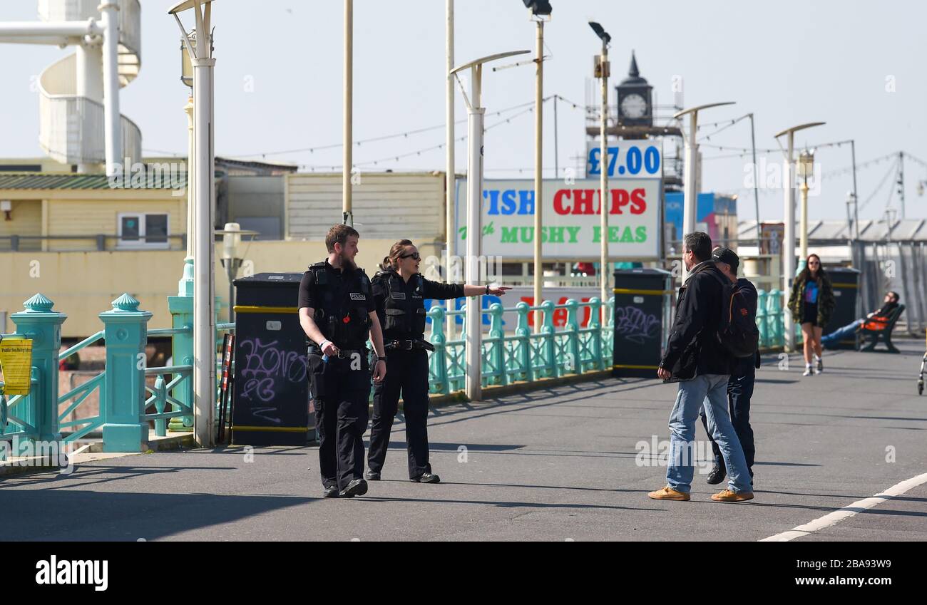 Brighton UK 26th March 2020 - Police officers chat to people walking along Brighton seafront making sure the public are obeying social distancing guidance on day three of governments lockdown restrictions during the Coronavirus COVID-19 pandemic crisis . Credit: Simon Dack / Alamy Live News Stock Photo