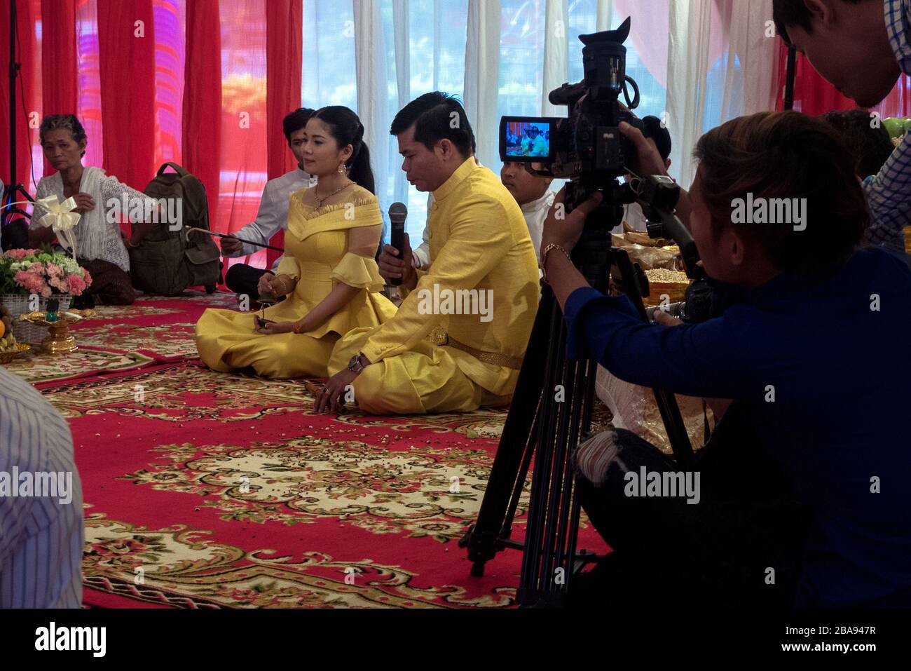 Kampot, Cambodia, Asia: a Cambodian married couple recites the promise of marriage while a video operator shoots a video of the ceremony Stock Photo