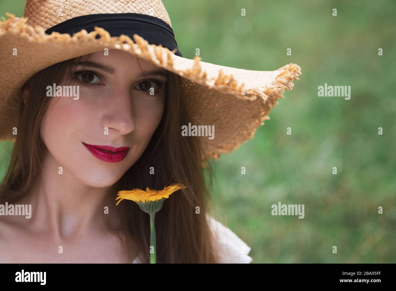 Young attractive girl holds a summer wildflower. She enjoys nature, the smell of flowers, outdoor recreation. Stock Photo