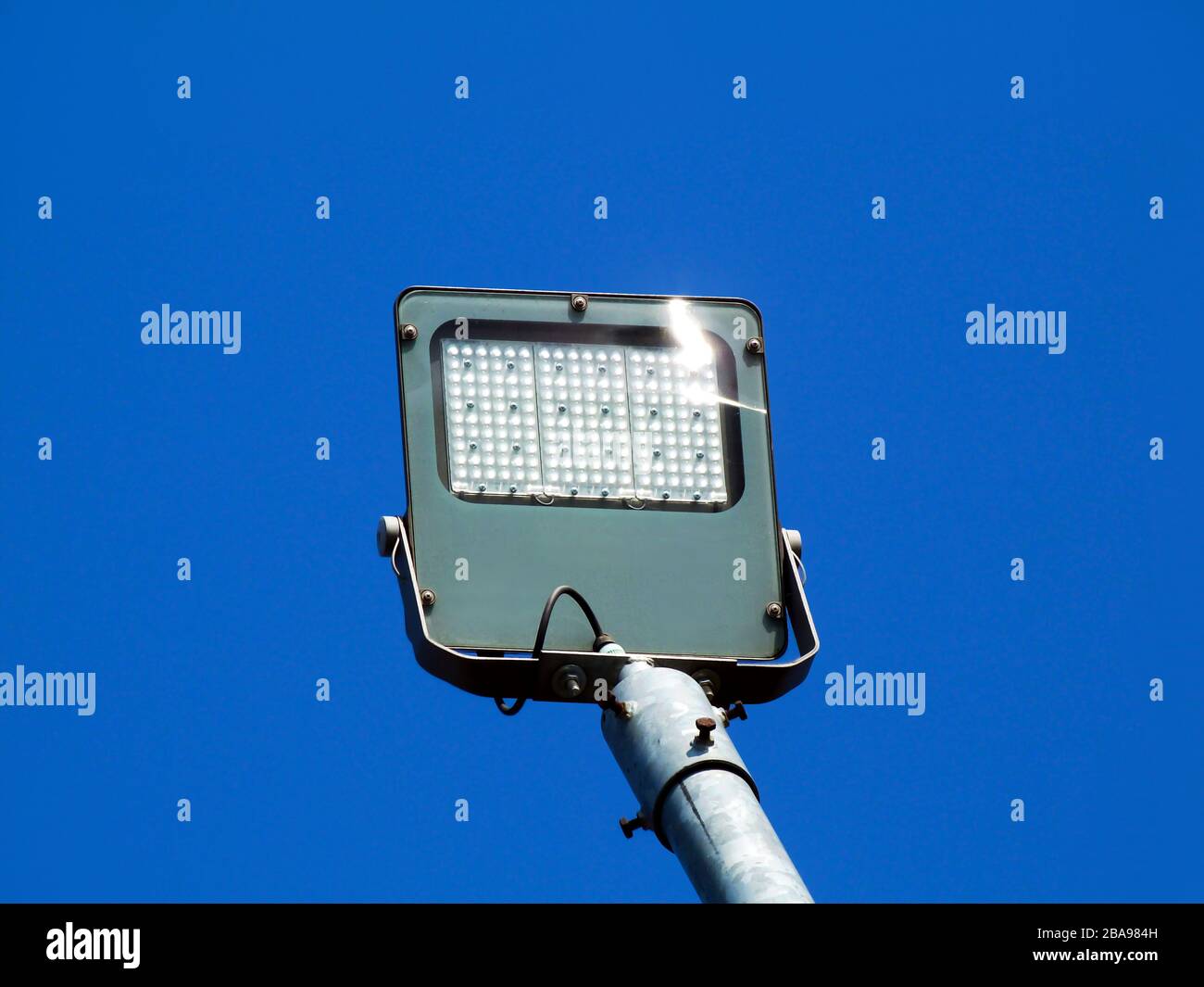 adjustable LED street reflector light with square lamp head under blue sky  with cables and tilted head on galvanized steel pipe pole. low angle view  Stock Photo - Alamy