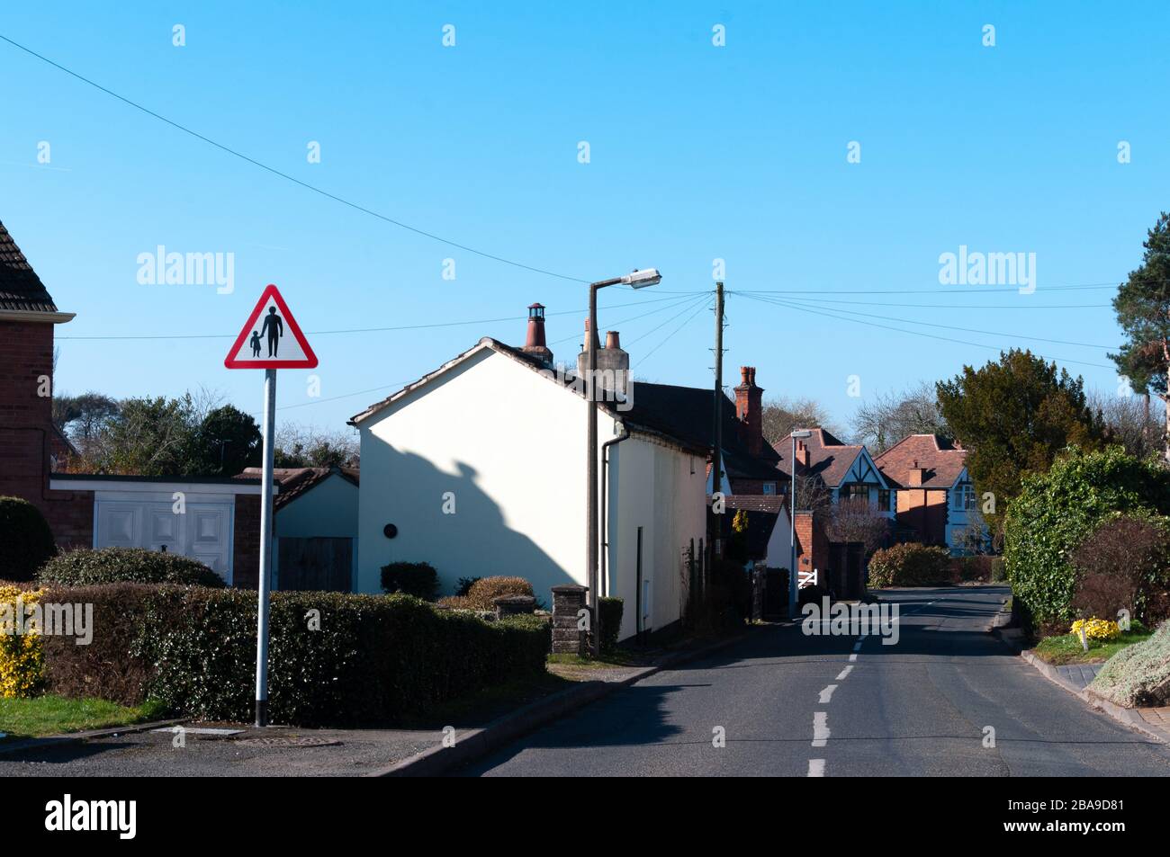 Triangular road safety warning sign for pedestrians in road or no footway. Isolated biside road. Lickey End, Bromsgrove. Stock Photo