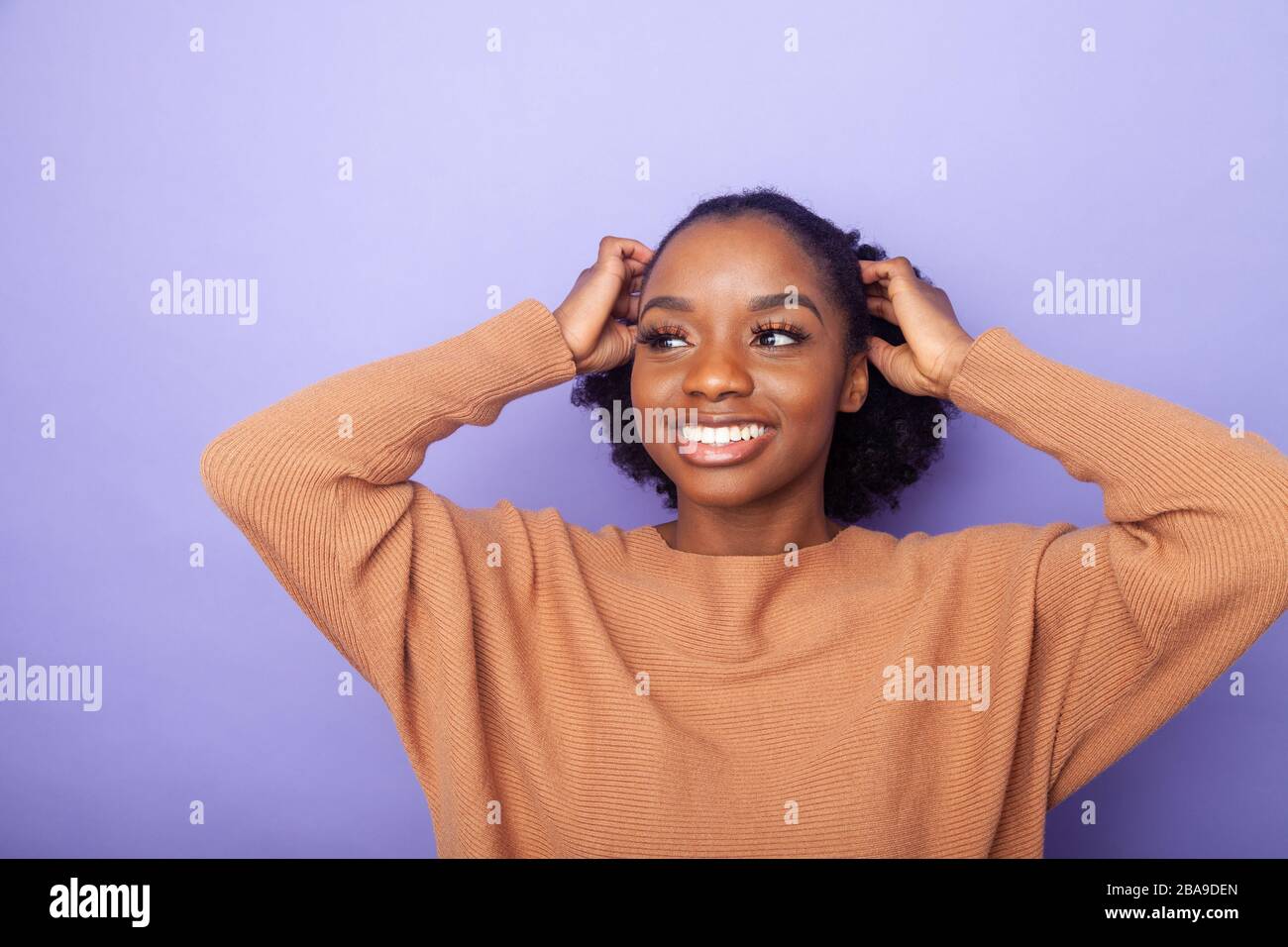 cheerful young black woman with hands next to her head Stock Photo