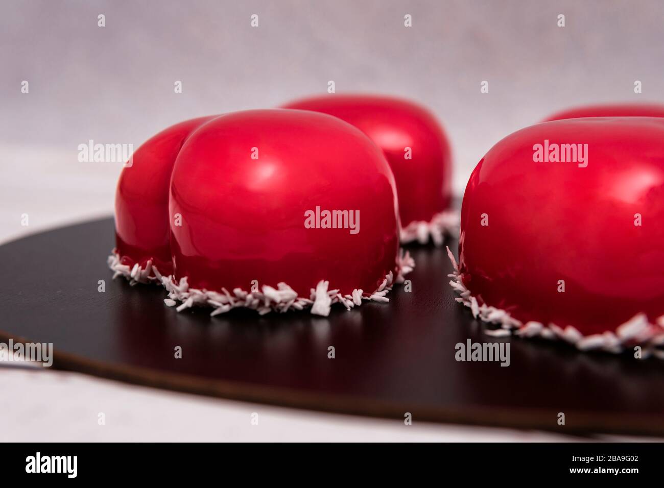 Close-up of mousse cake with red mirror glaze. Cooking french dessert. Frozen mirror icing on the cake. Baking and confectionery concept. Stock Photo