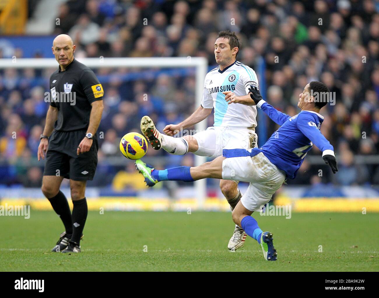 Everton's Steven Pienaar (right) slides in on Chelsea's Frank Lampard (centre) as match referee Howard Webb (left) looks on Stock Photo