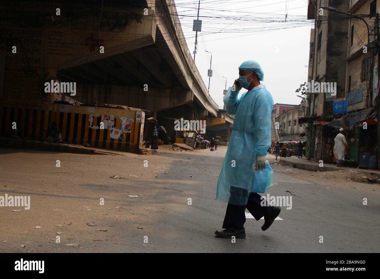 A man wearing a protective suit walks across a deserted road amid Coronavirus threats in Dhaka. The Institute of Epidemiology, Disease Control and Research (IEDCR) has confirmed that five more people have tested positive for Covid-19 in the last 24 hours. The number of total coronavirus patients in the country stands at 44. Stock Photo