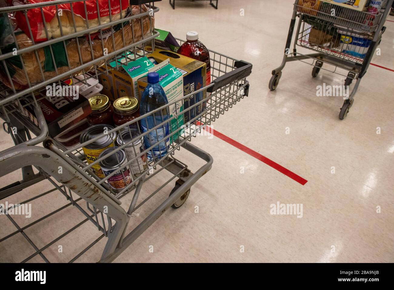 March 23, 2020 - Montreal, Qc, Canada : Line up and grocery Carts with decals markers on floor, supermarket, Coronavirus (COVID-19) Pandemic Crisis Stock Photo