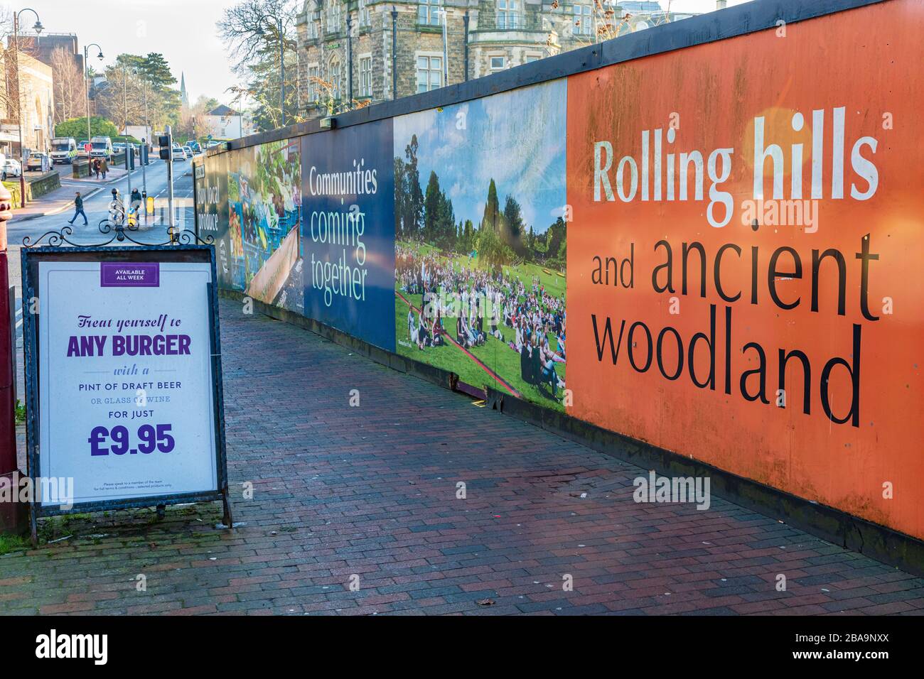 Advertising hoardings around a town centre development. A burger ad on the pavement, Tunbridge Wells, Kent, UK Stock Photo