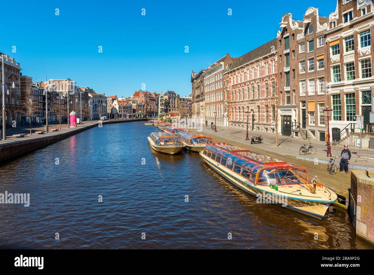 Group of empty tour boats docked in an Amsterdam Netherlands canal because of coronavirus outbreak Stock Photo