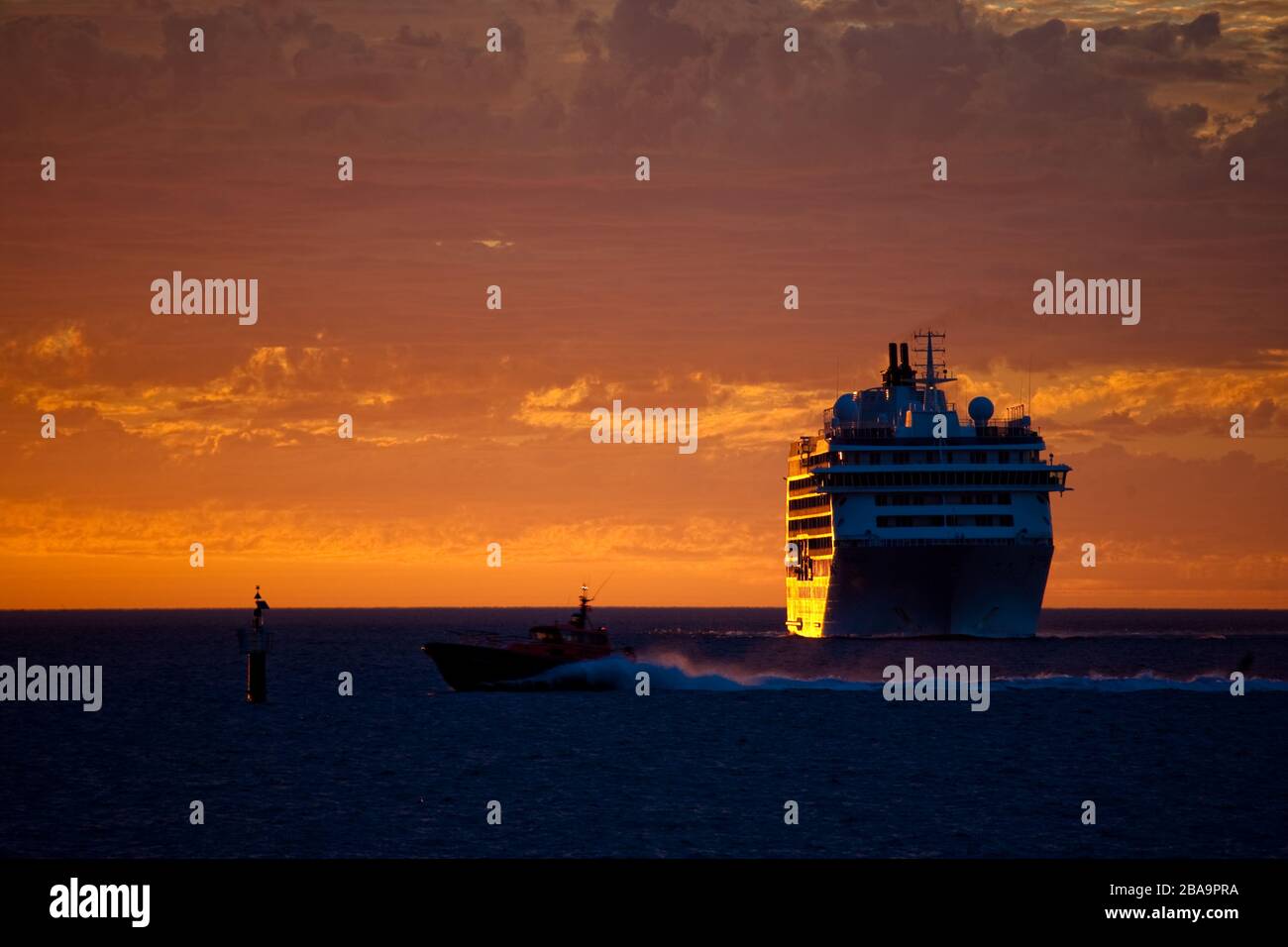 A cruise anchored off-shore soaks in an epic blood red sunset.  Western Australia Stock Photo
