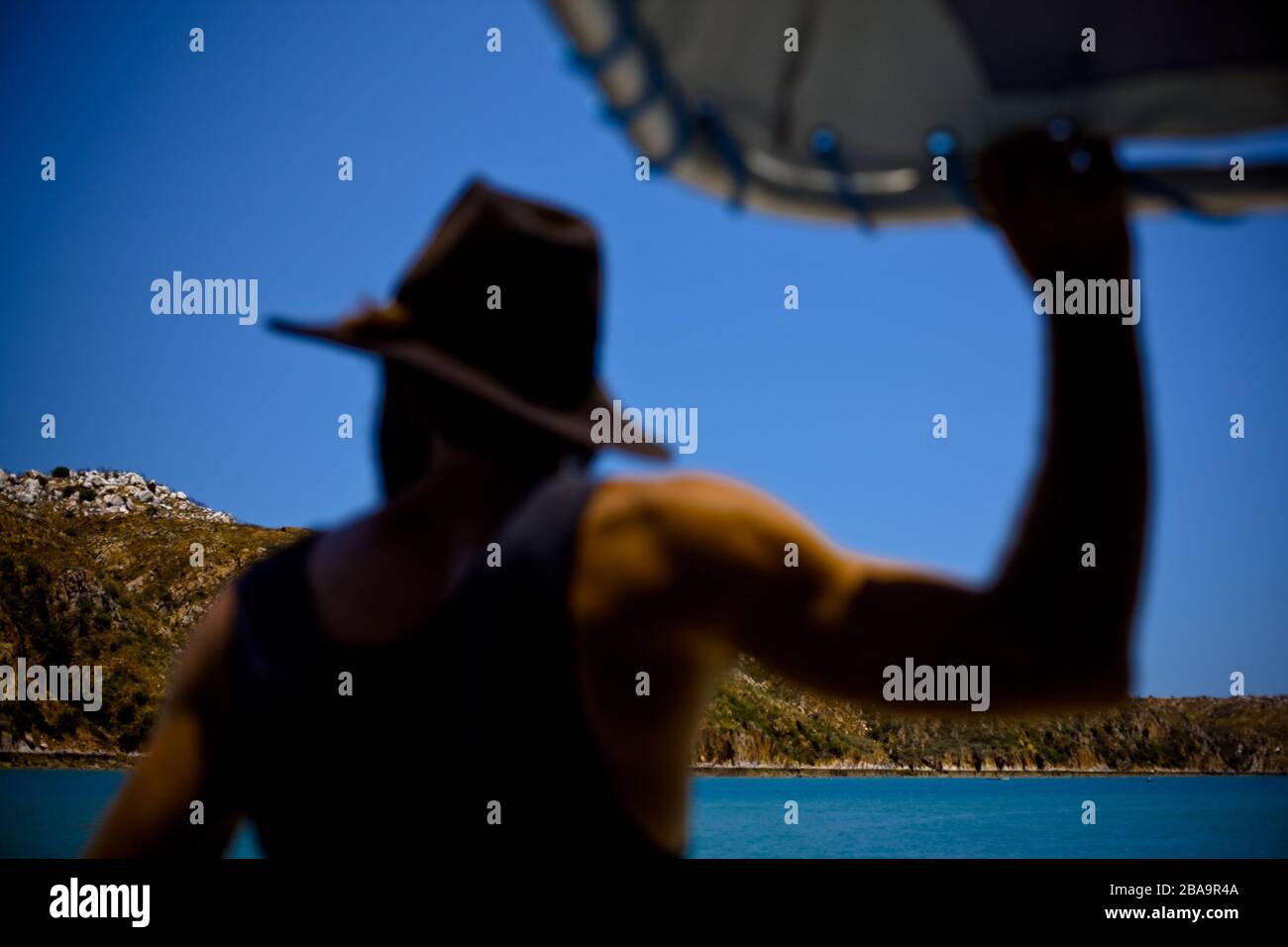 A man in wears an iconic symbol of Australian culture, thinks pensively as he journeys between islands in Western Australia. Stock Photo