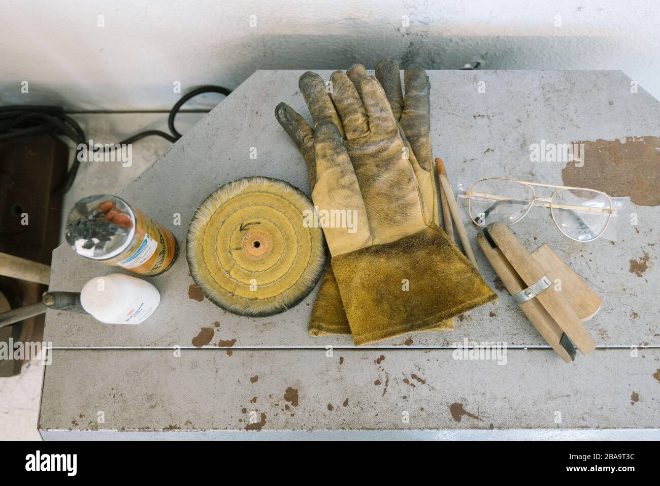 Dirty gloves rest by glasses and assorted crafting tools and resources Stock Photo