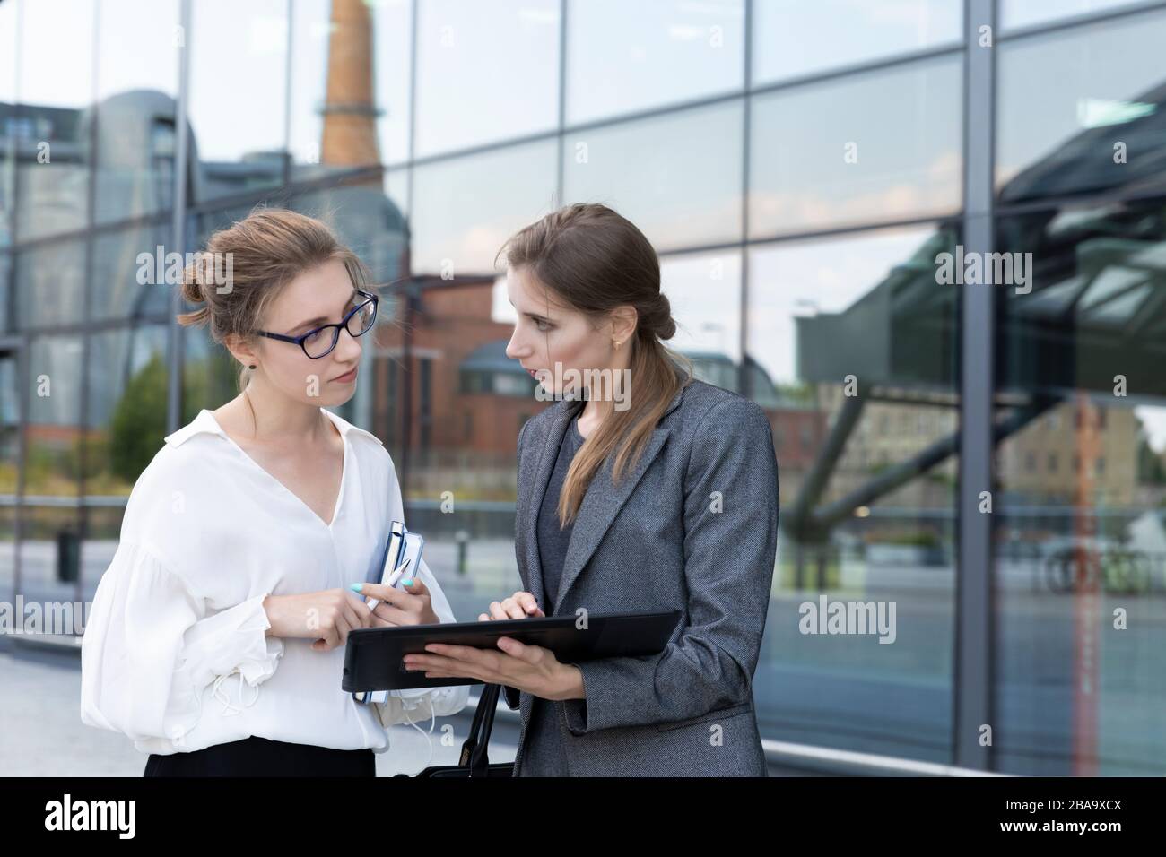 Two young and beautiful business women are standing against the ...