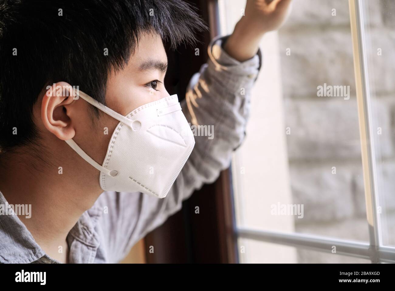 Wearing a mask of the boy looked out through the window Stock Photo - Alamy