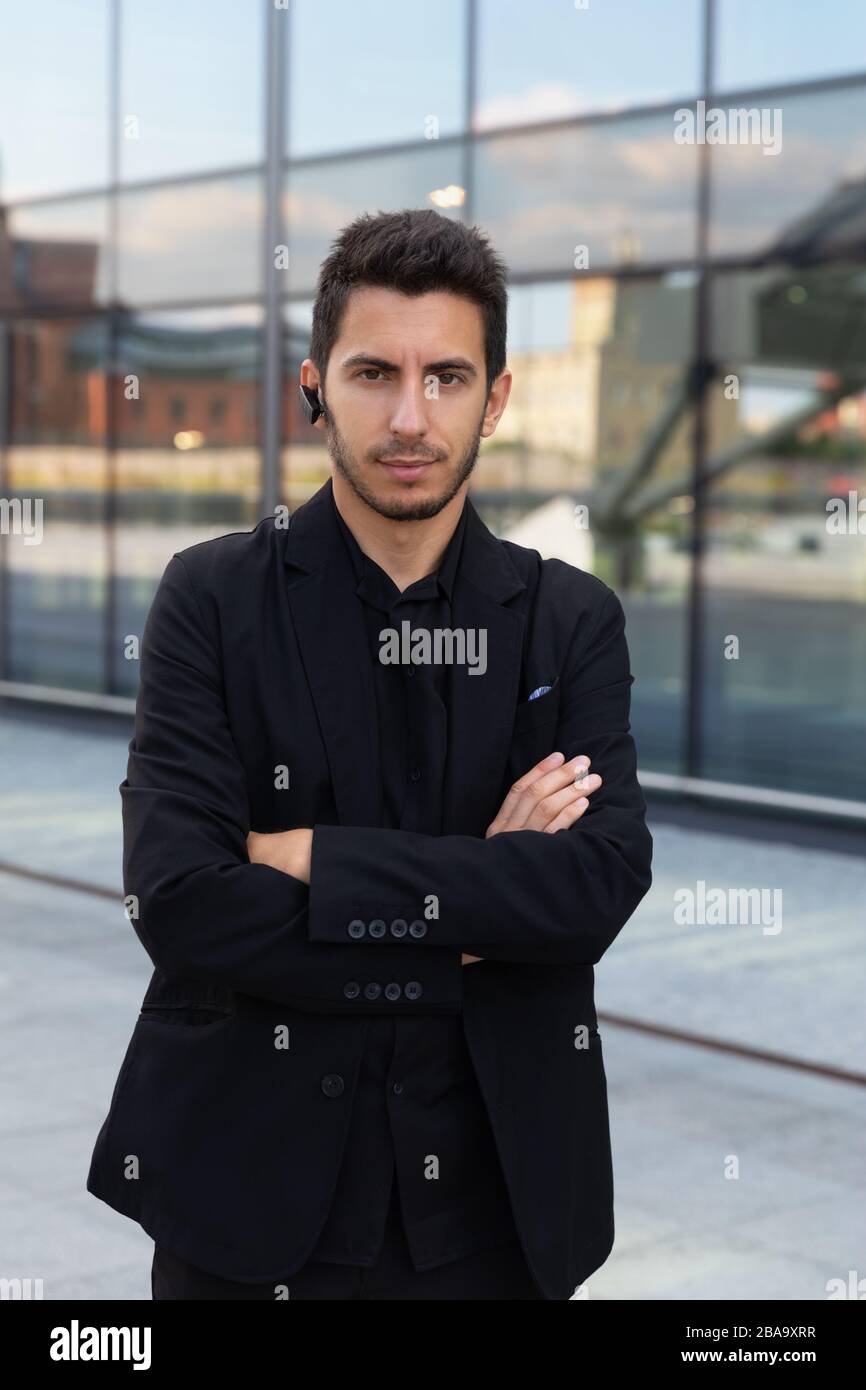 A young handsome man is standing in a black business suit on the ...