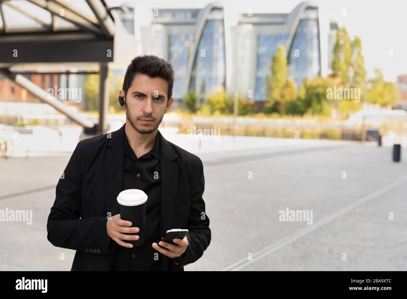 A young handsome man is standing in a black business suit on the ...