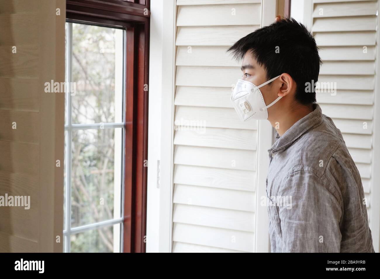 Wearing a mask of the boy looked out through the window Stock Photo - Alamy