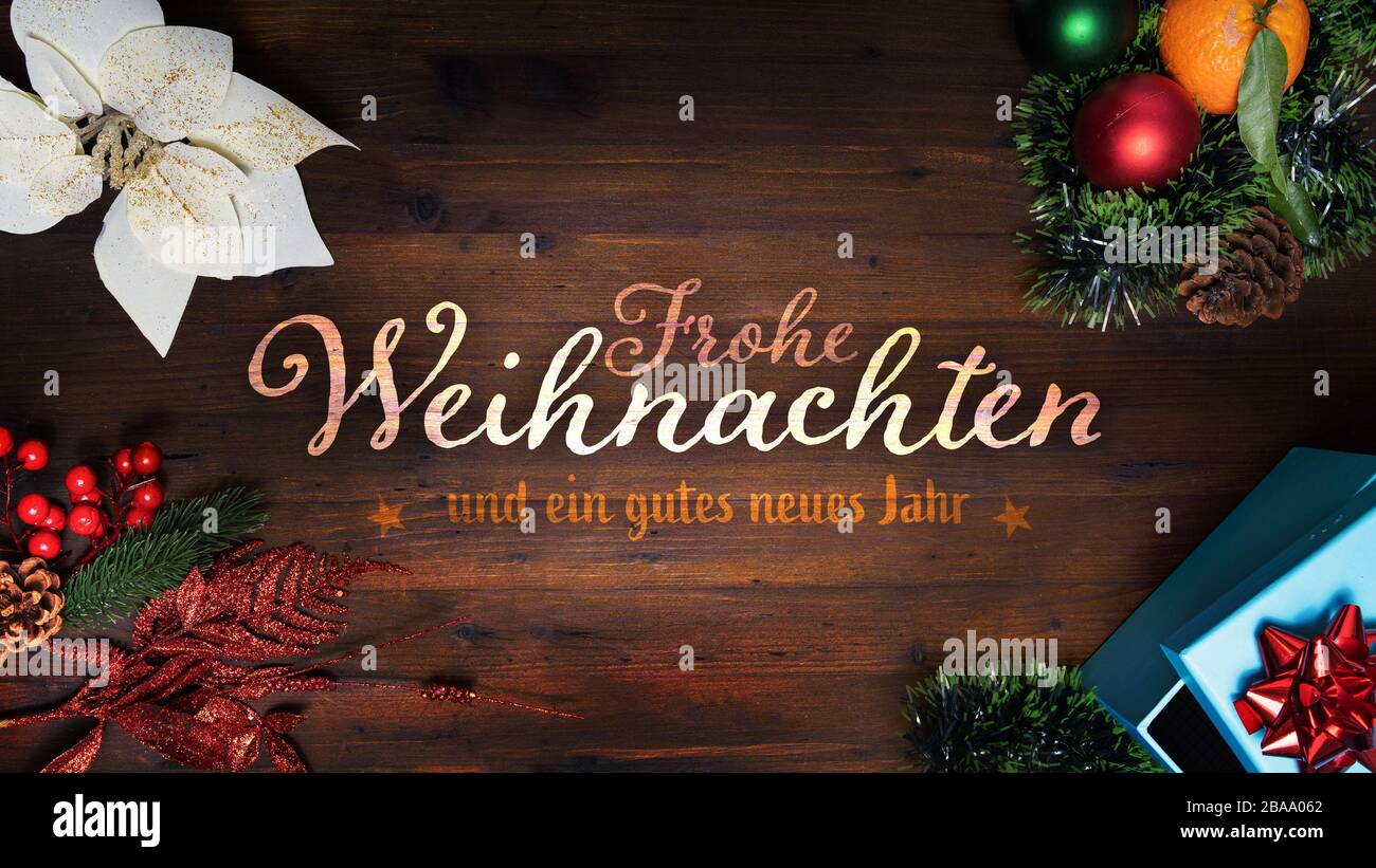 “Frohe Weihnachten und ein gutes neues Jahr” t.i. Merry Christmas and Happy New Year in German language on a wooden background with decoration horizon Stock Photo
