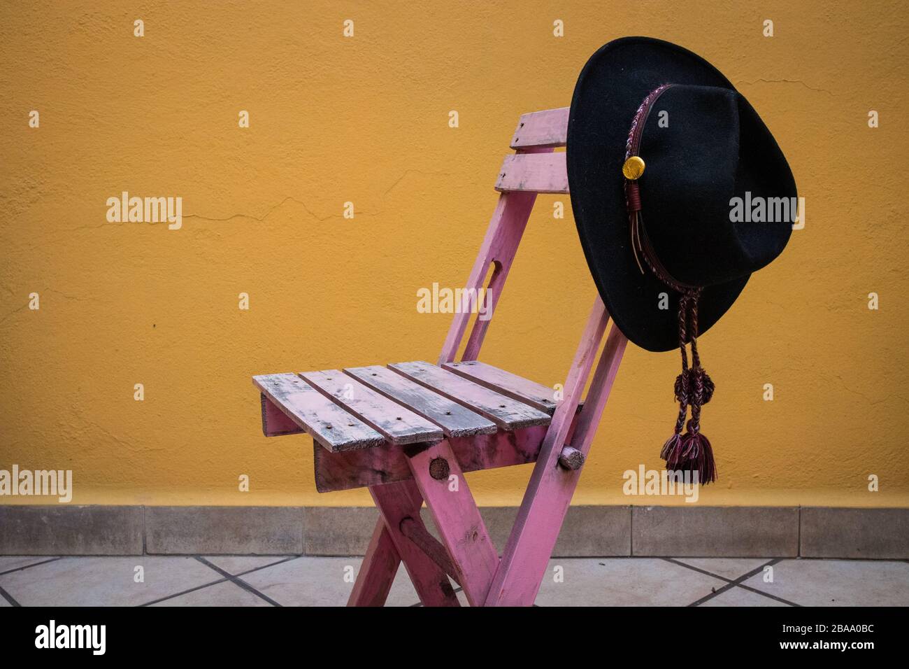 Black Cowboy Hat Hanging on Pink Chair Stock Photo