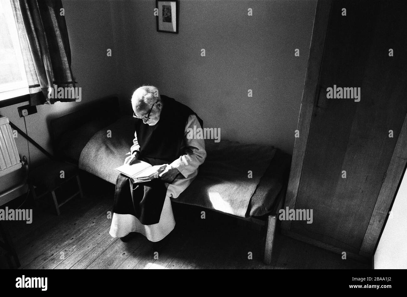 A monk reading in his room at Sancta Maria Abbey at Nunraw, East Lothian, home since 1946 to the Order of Cistercians of the Strict Observance. Around 15 monks were resident at Nunraw in 1996, undertaking a mixture of daily tasks and strict religious observance. The present purpose-built building dates from 1969 when the monks moved from the nearby Nunraw house. Stock Photo
