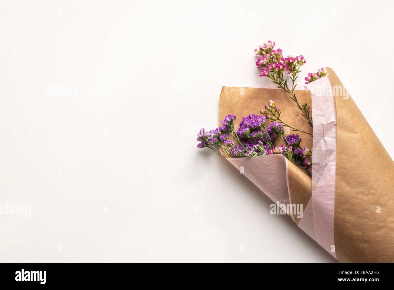 Minimal White bacground, Bunch of flowers, brown paper, pink purple wildflowers feminine concept, female concept, nature, beauty, delicate Stock Photo
