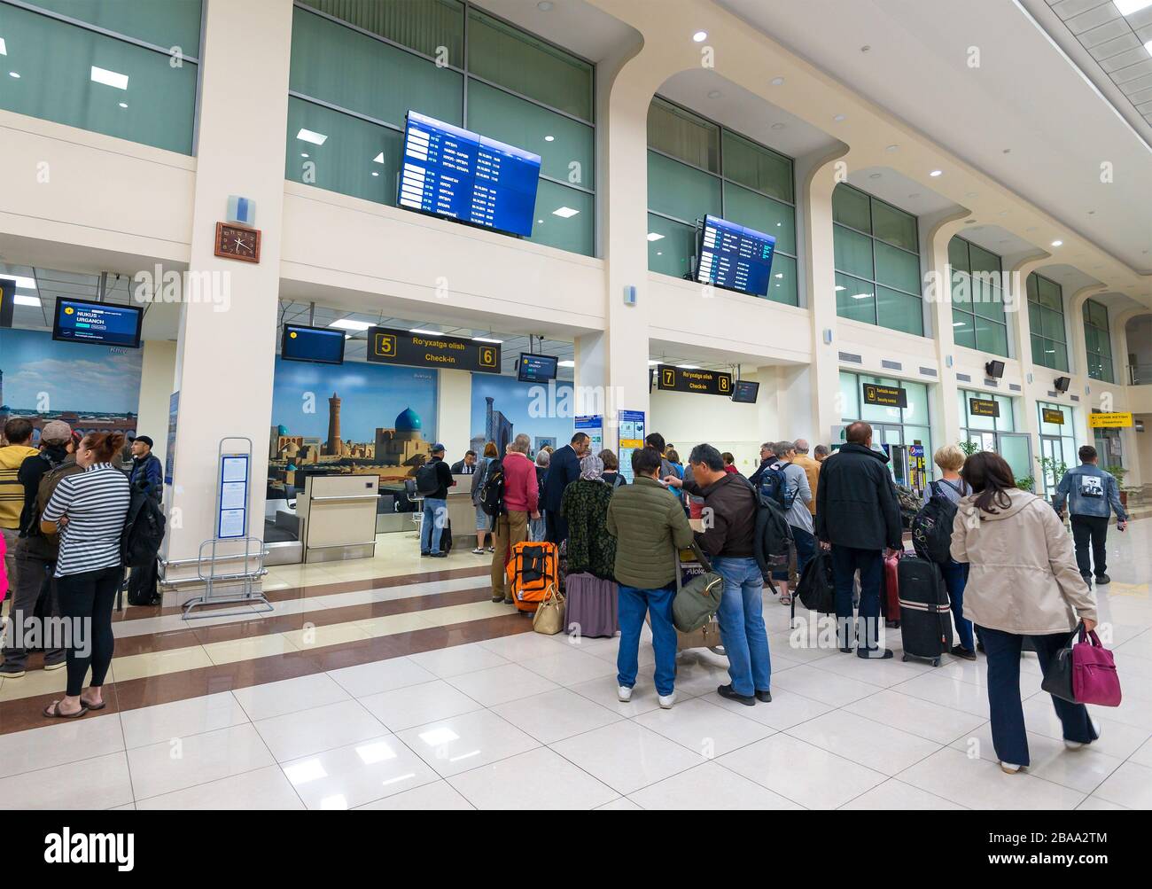 Domestic terminal check-in desks with passengers lined up in the interior of Islam Karimov Tashkent International Airport in Uzbekistan. Stock Photo