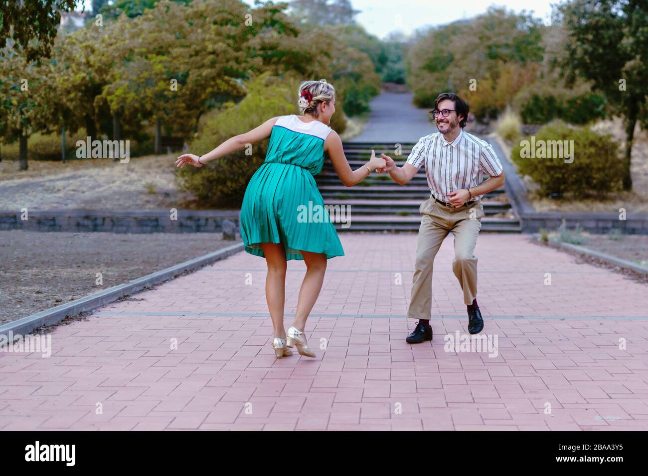 Couple dancing swing lindy-hop in outdoor in the park. People having fun dancing vintage music together in the nature. Stock Photo