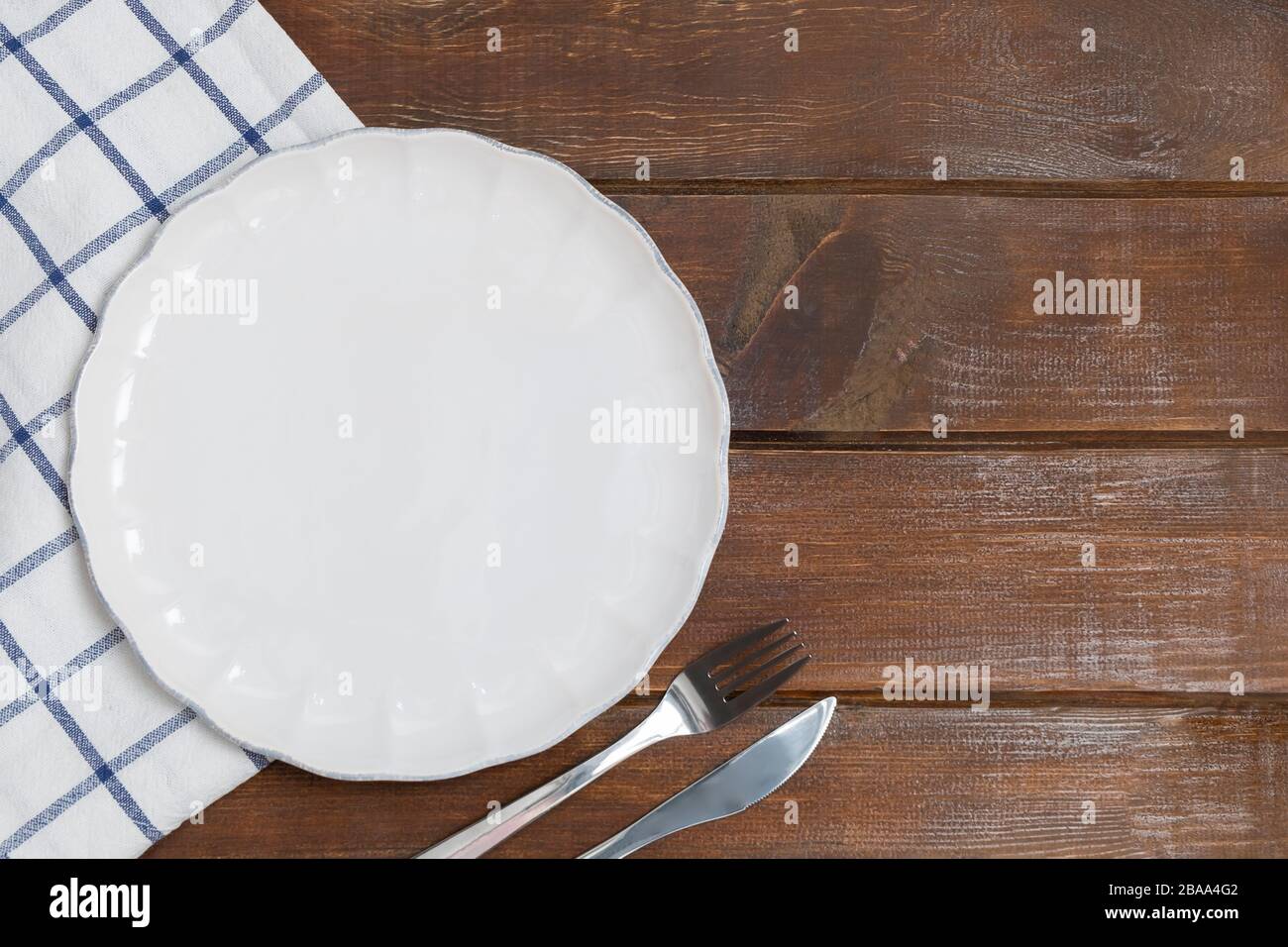 Blank flat plate with kitchen napkin on wooden table background with copy space, mockup, flat lay Stock Photo