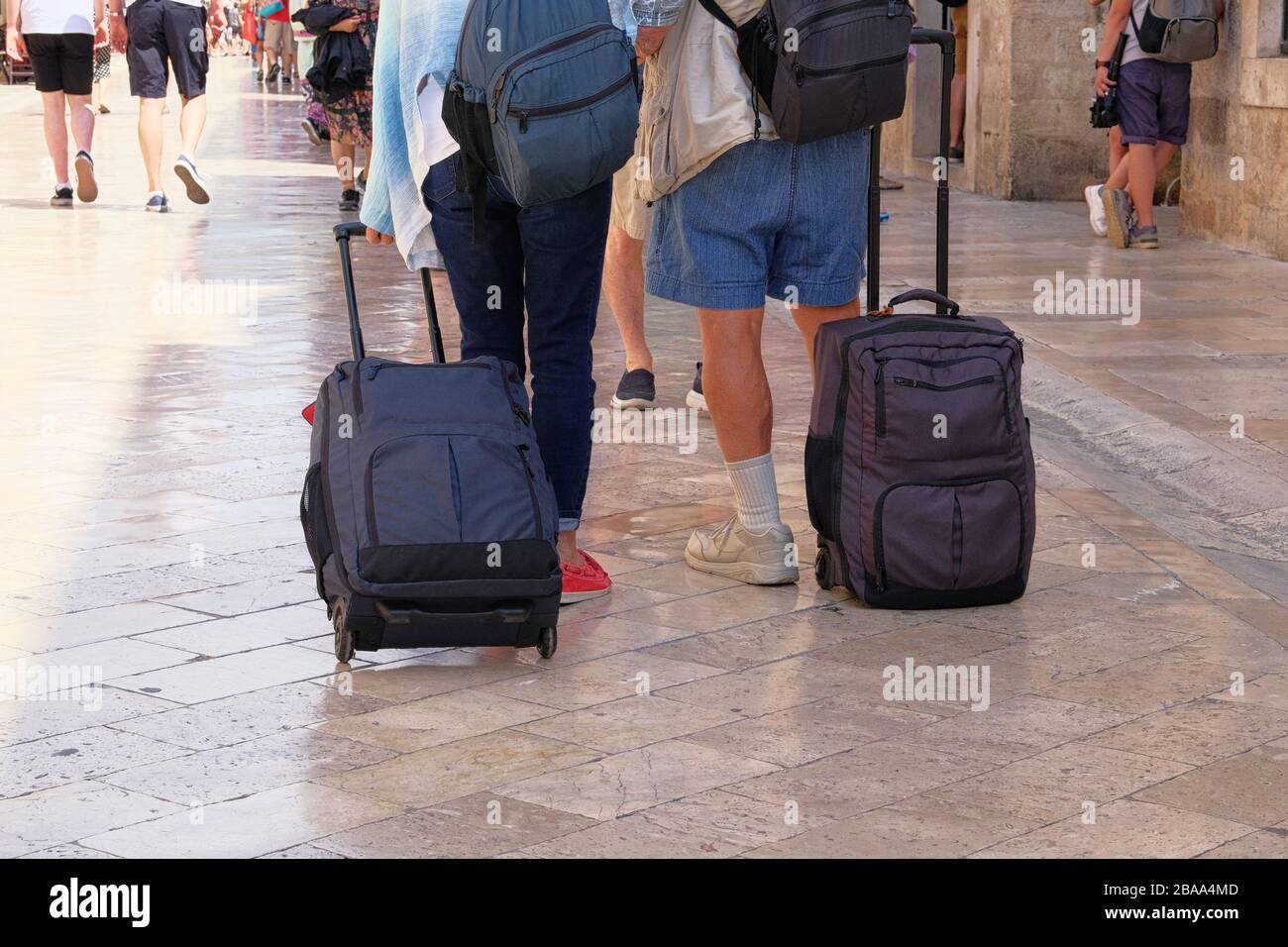 Travelers is walking with luggage on street, goes to city hotel