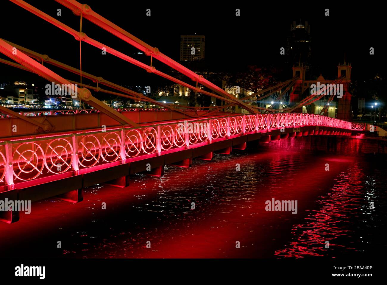 The Cavenaugh bridge, the only suspension bridge on the Singapore river, illuminated in red at night. Stock Photo