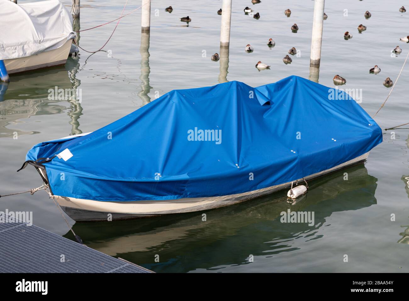 white fishing boat with blue boat cover, cloudy sky and brown