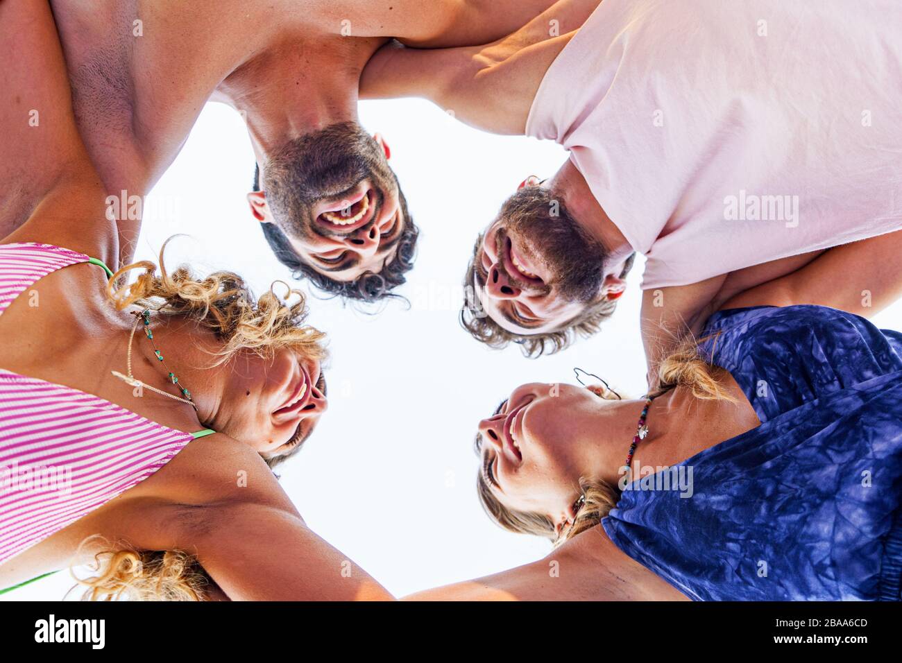Group of twenties young people arm on shoulders in a circle. Best friends having fun in the summer watching each other. Trust and friendship concept. Stock Photo