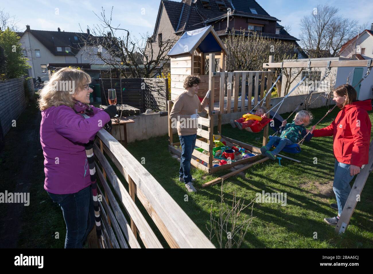 Social distancing: A grandmother (left) came to a garden fence during coronavirus pandemic to celebrate her birthday with her two grandchildren Stock Photo