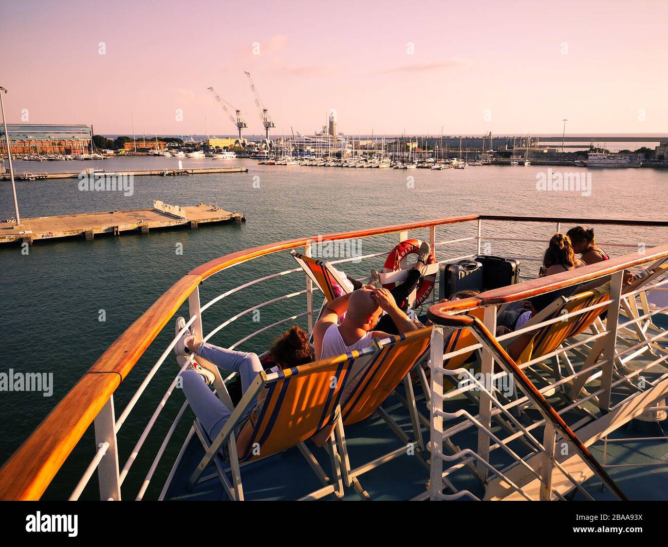 Passengers of a ferry relax on deck chairs while going on holiday. Stock Photo