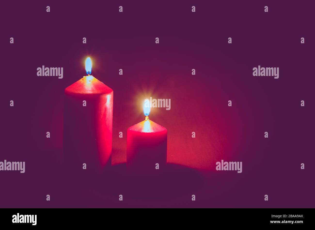 two red illuminated burning wax candles with black copy space