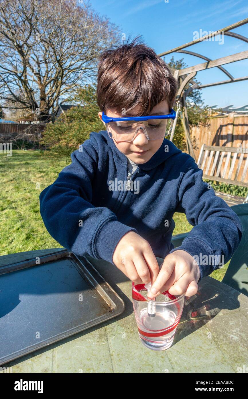 A young boy does a science experiment in the garden mixing vinegar and