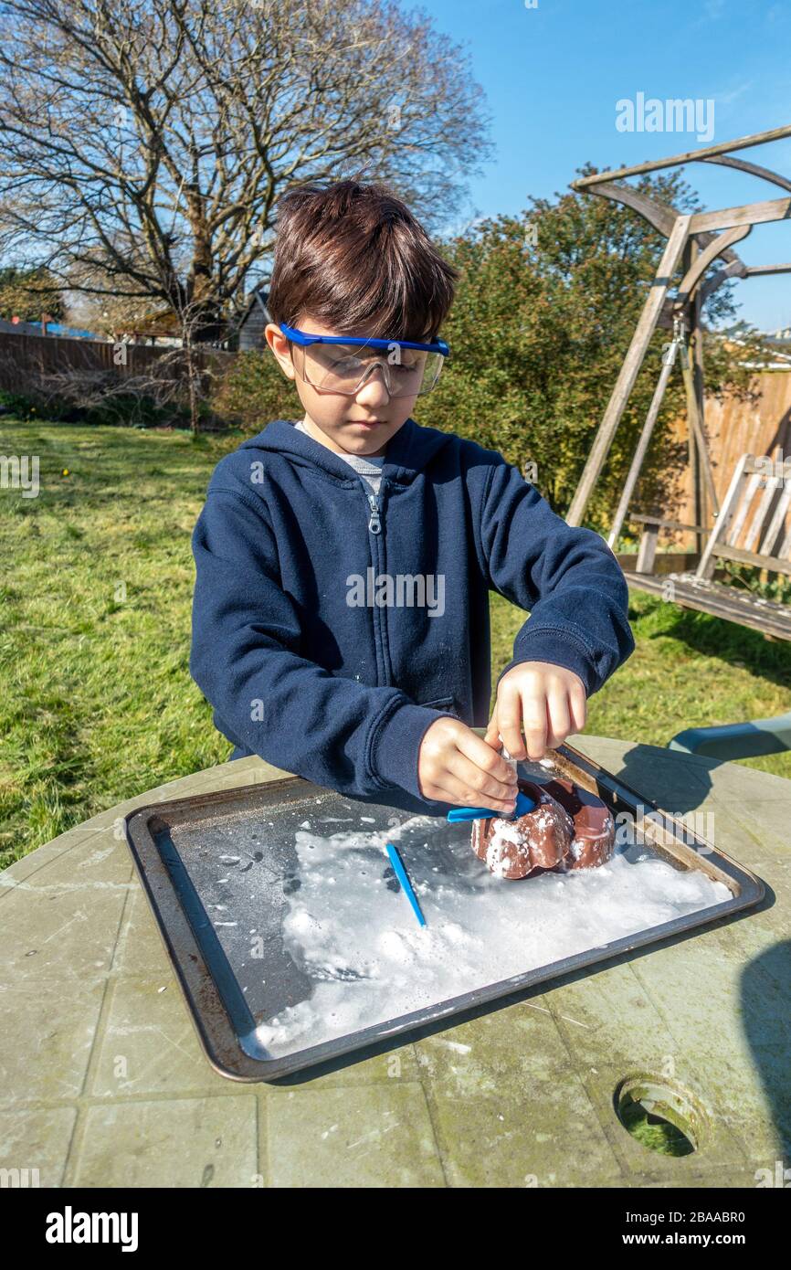 A young boy does a science experiment in the garden mixing vinegar and